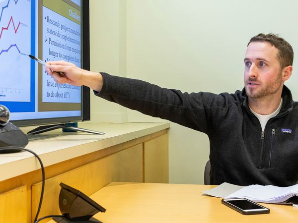 A student in the Criminology Research Group points to the projection screen while discusses a project he and his colleagues have been working on.