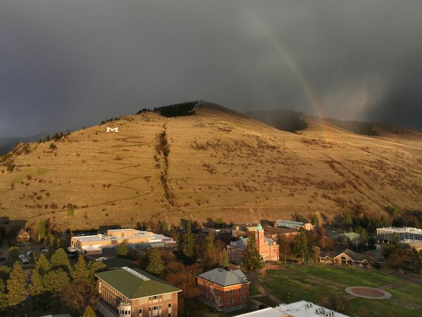 Mount Sentinel basked in sunlight after a storm with a rainbow overhead