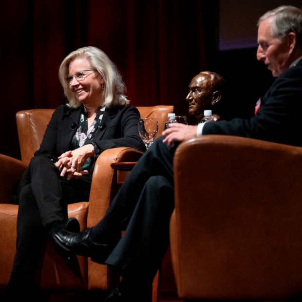 Liz Cheney and Marc Racicot talking while sitting in chairs