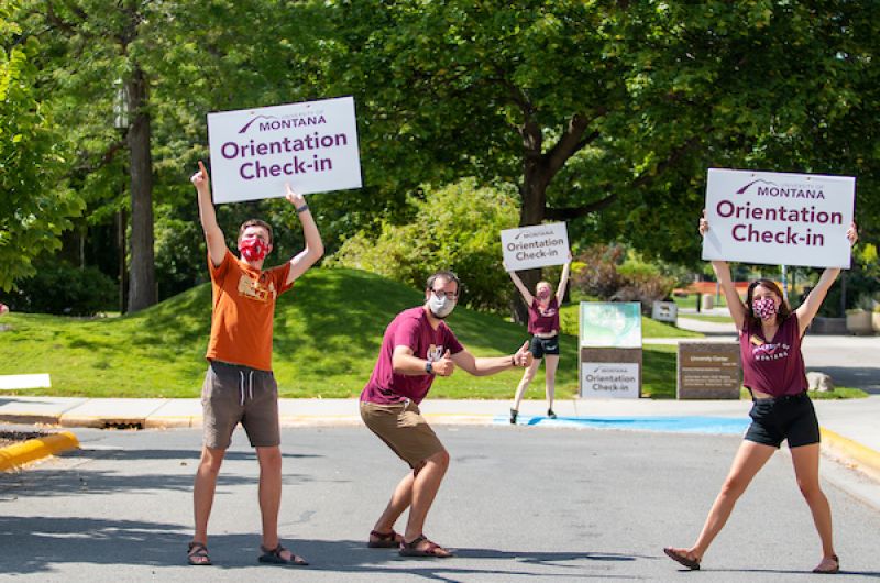 Three Advocates hold Orientation Check In signs