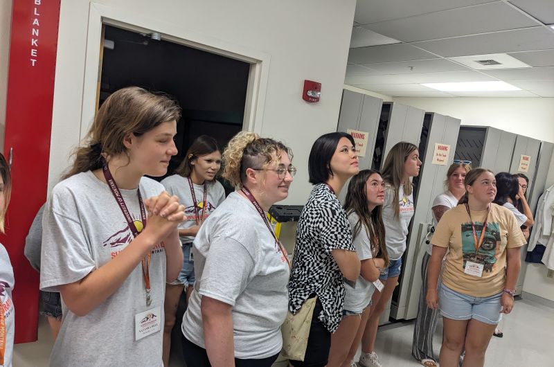 students look up at a display out of frame