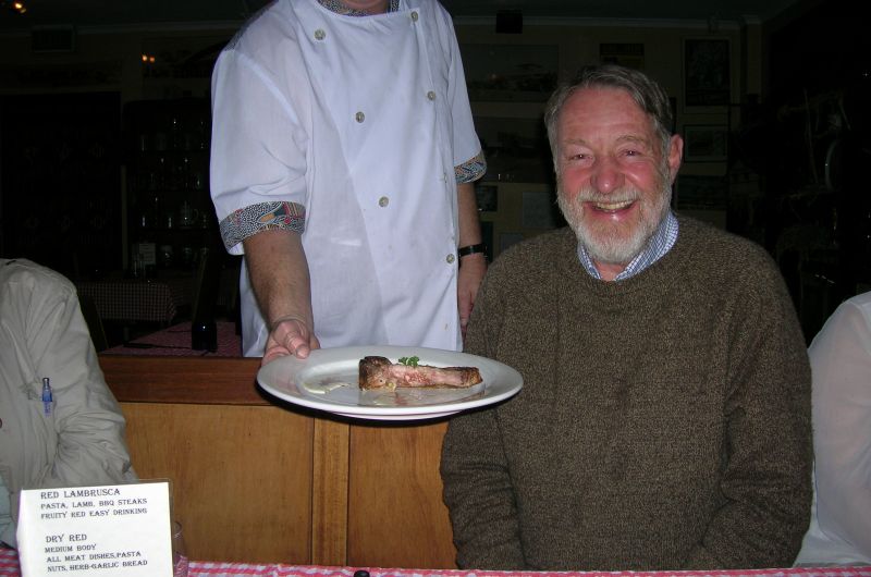 Don smiles while a waiter hands a plate with food.