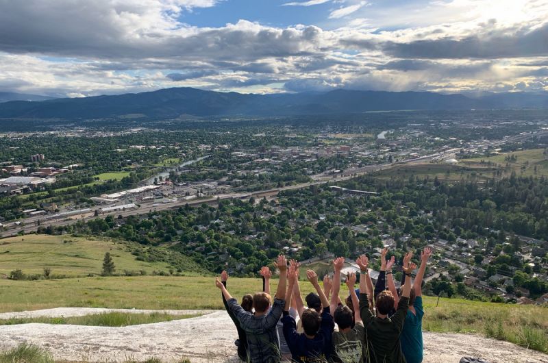 Schwanke participants sitting on top of Mount Sentinel with their arms up in the air 