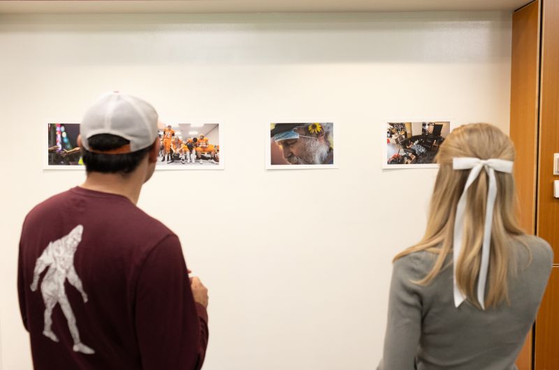 People hang photography in a gallery.