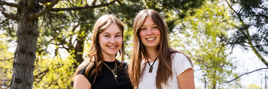 Two UM students stand together for a photo on campus