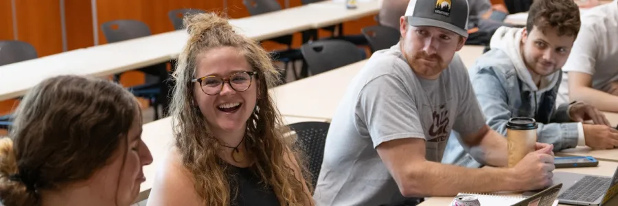 Five UM students sitting at a table and conversing in a Communication Studies class at the �����ؿ�.