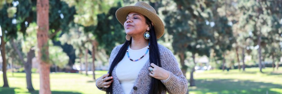 woman smiling with their eyes closed enjoying the sunshine outside on the UM campus