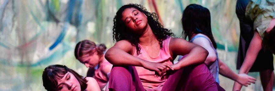 student stretching their neck while sitting on a stage with other students in the background